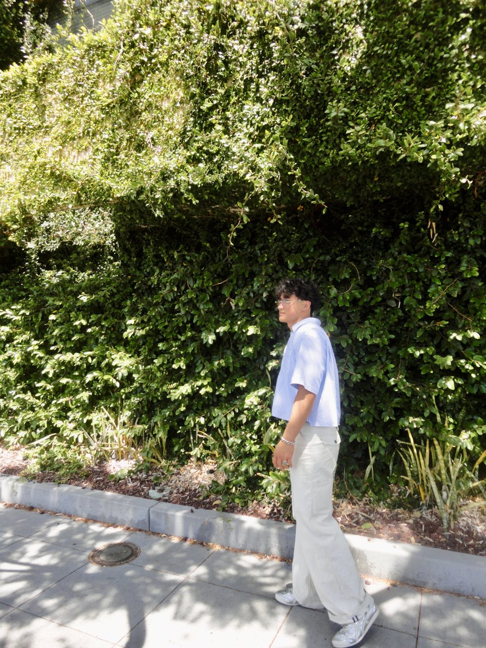 Johnny Chai walking past a hedge in San Diego